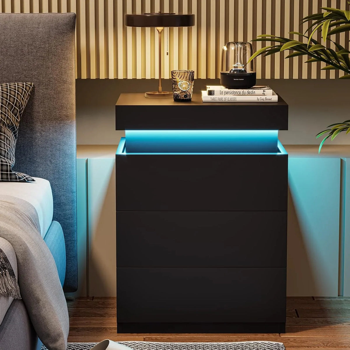 Modern black LED nightstand with blue ambient lighting next to a grey upholstered bed.
