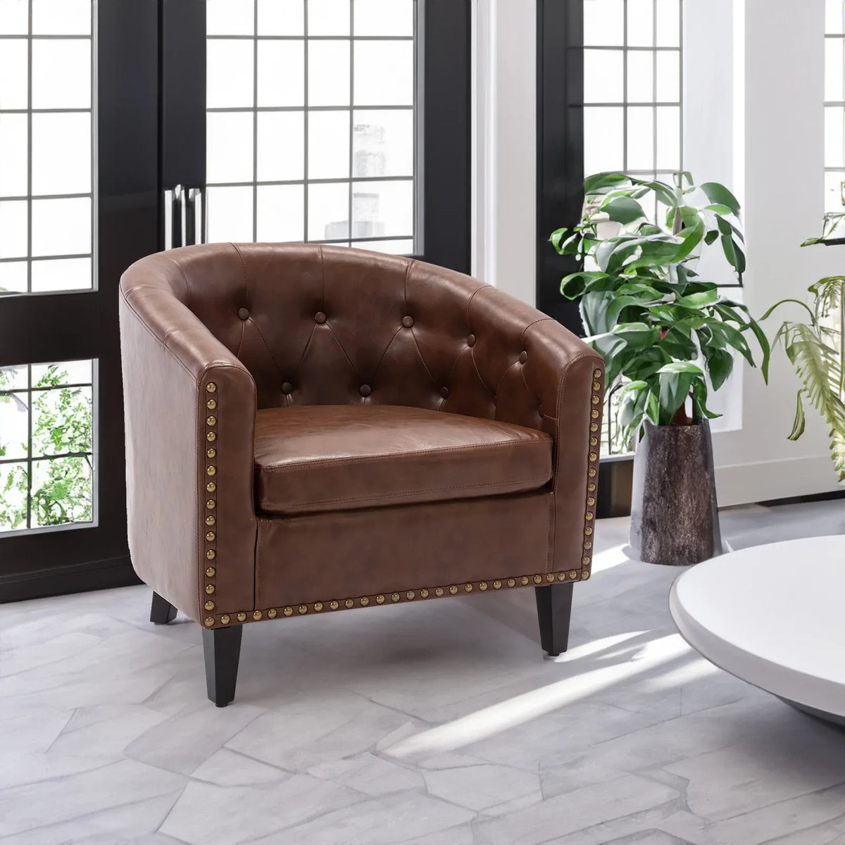 Eprolo brown PU leather tufted barrel chair with nailhead trim in a bright living room.