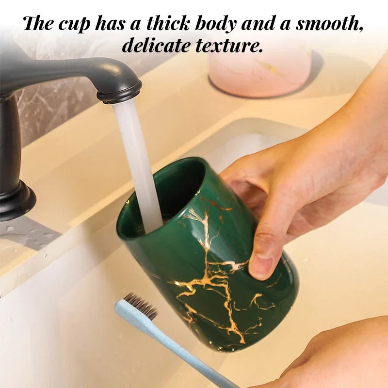Hands rinsing a luxury eprolo green ceramic cup with gold marble veins in a bathroom sink.