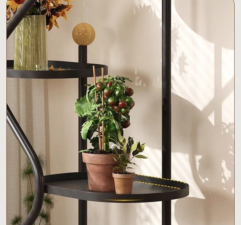 Black floor standing flower rack with potted plants and decorative vase in a living room.