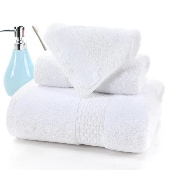Set of three white 100% cotton terry cloth bath towels stacked with a light blue soap dispenser.