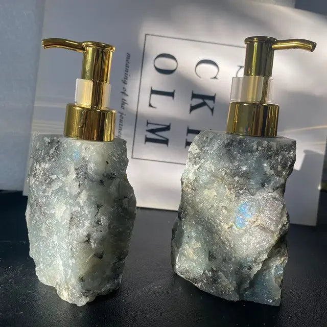 Two eprolo natural crystal stone liquid soap dispensers with gold pump tops.