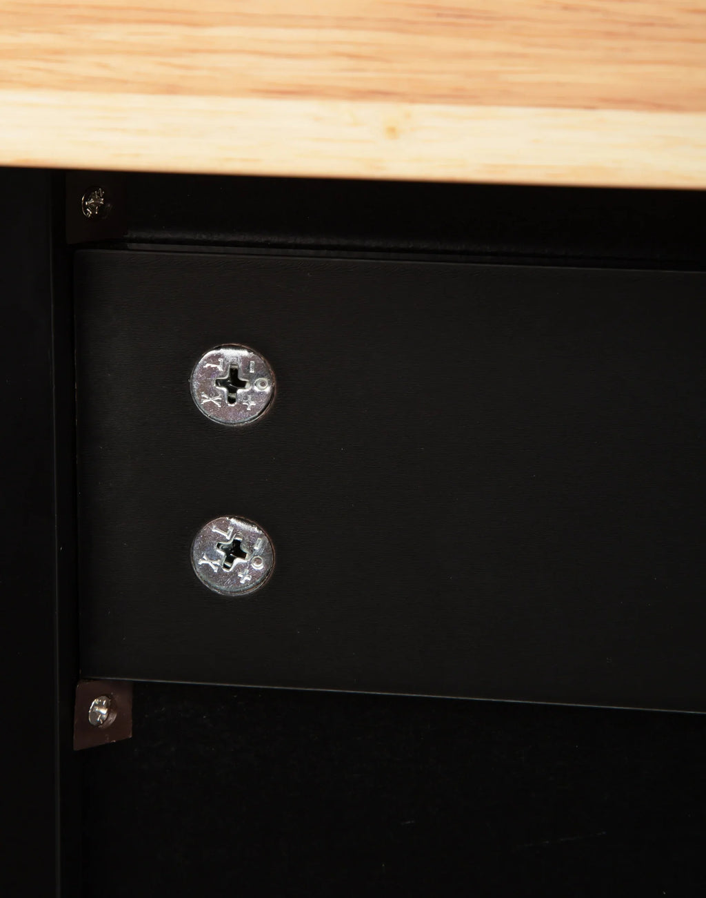 Close-up of screws securing a black metal frame to a rubber wood countertop of an eprolo kitchen island.