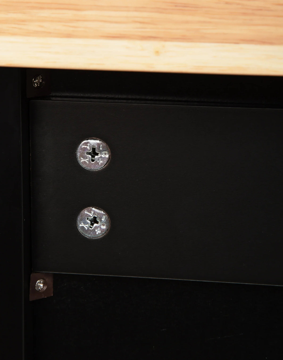 Close-up of screws securing a black metal frame to a rubber wood countertop of an eprolo kitchen island.