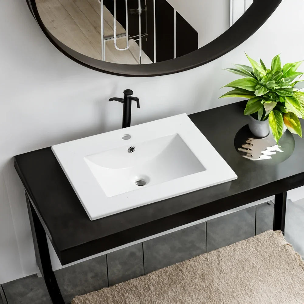 White 24 inch eprolo ceramic bathroom sink basin with black faucet on a dark vanity.