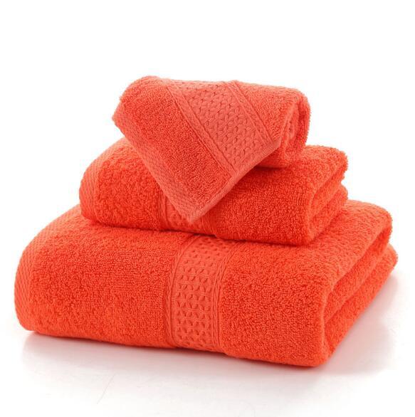 Set of three vibrant orange 100% cotton terry cloth bath towels stacked on a white background.