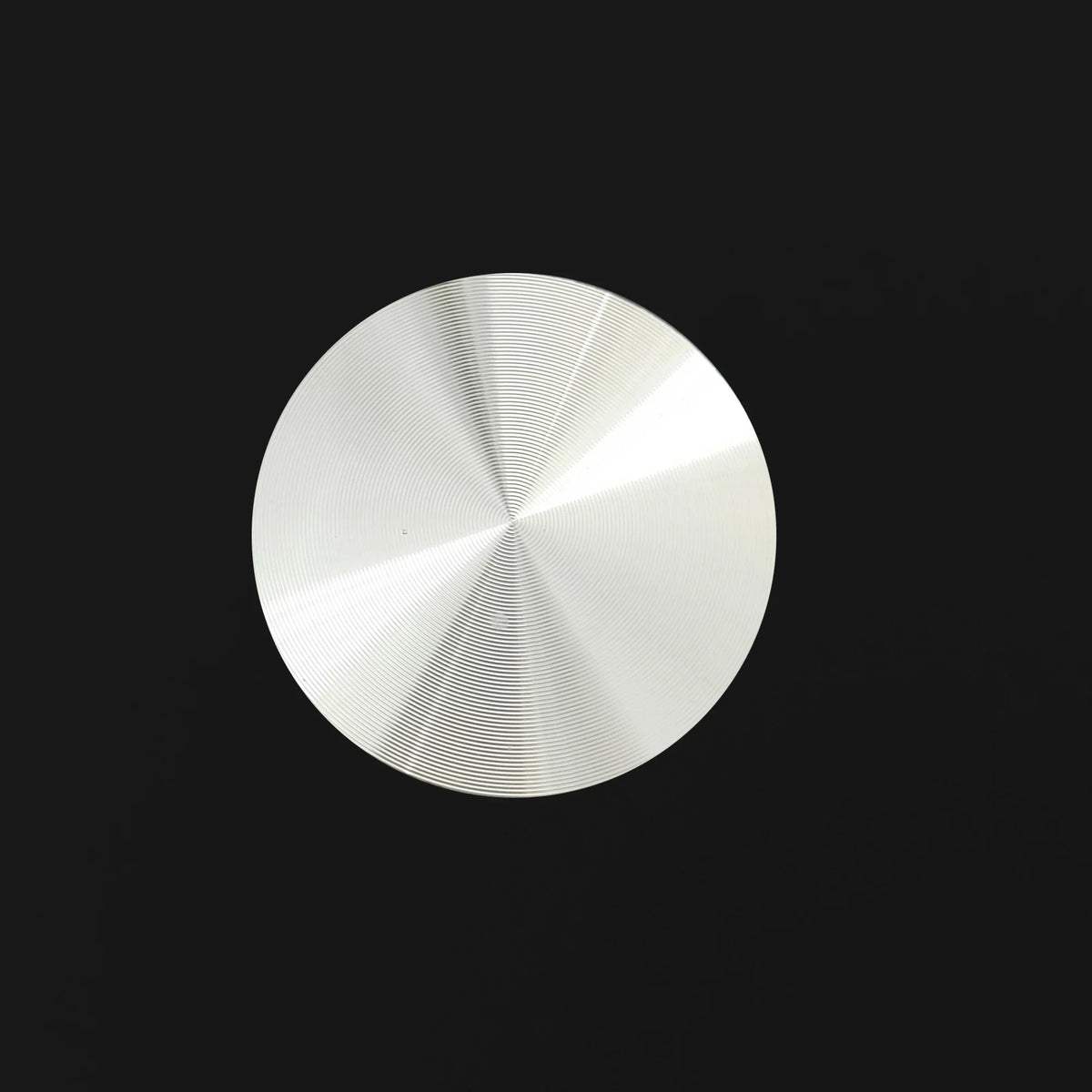 Circular brushed silver metal plate with concentric texture on a black background.