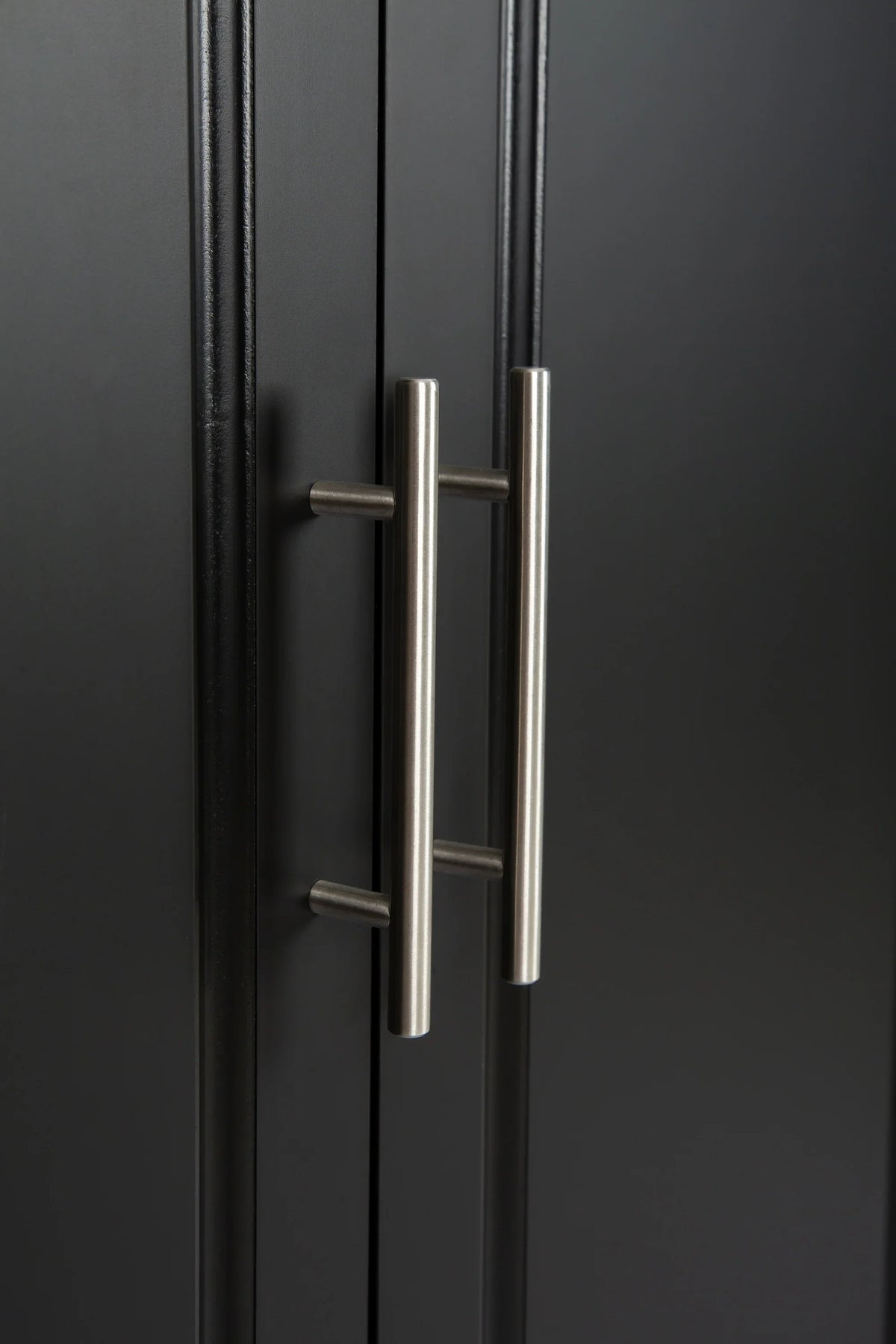Close-up of silver metal cabinet handles on a black eprolo kitchen island.