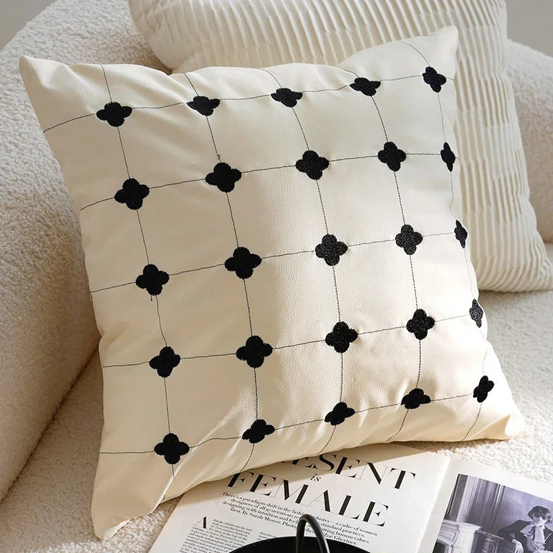 Eprolo cream-colored sofa pillow cover with black quatrefoil pattern on a white sofa.