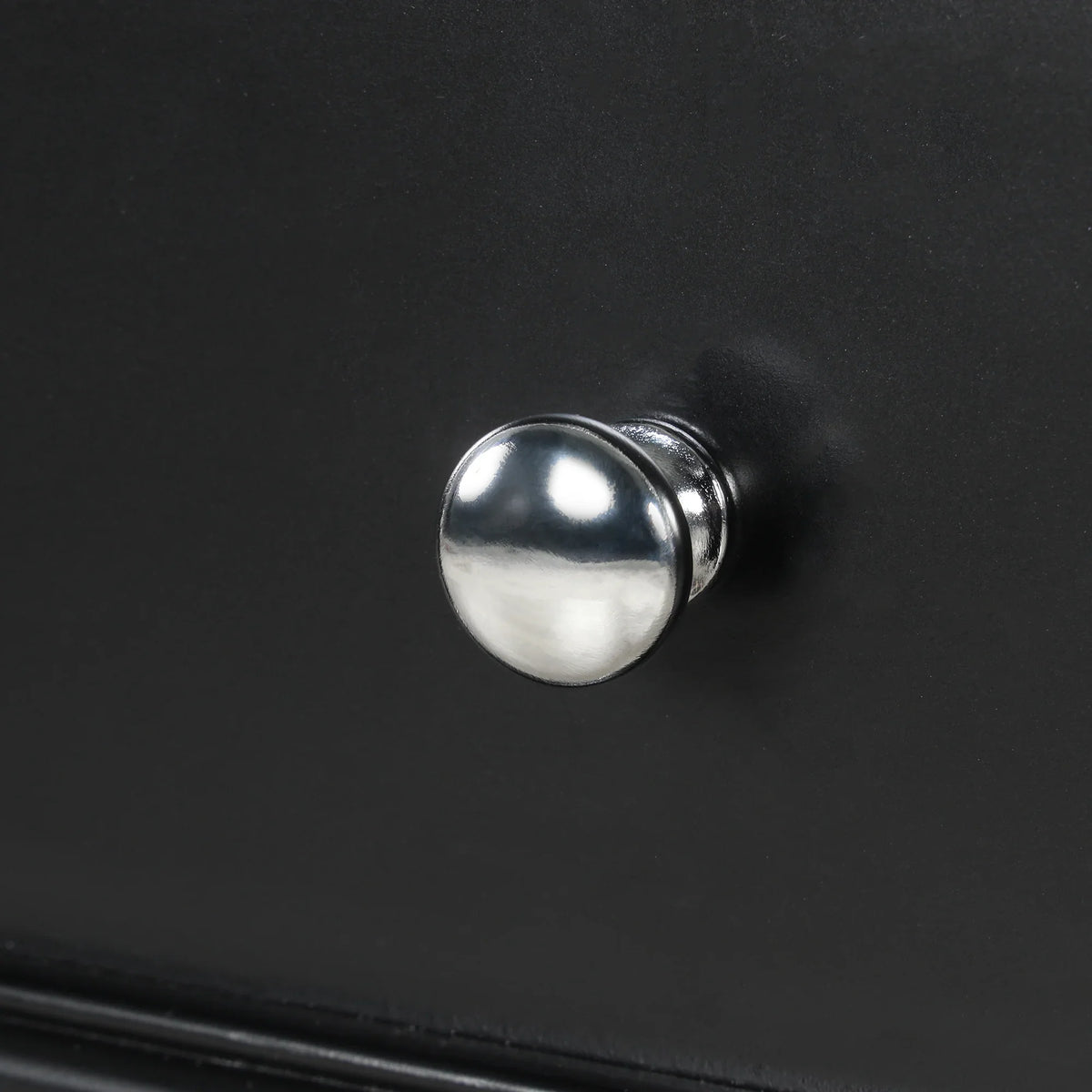 Close-up of a polished chrome knob on a black eprolo bathroom vanity drawer