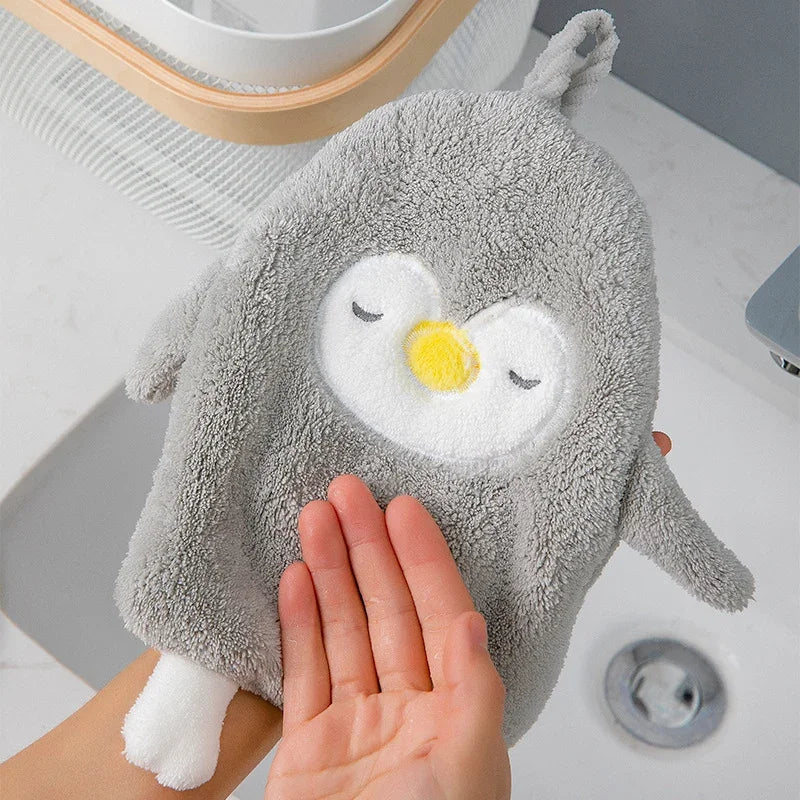 Cute penguin coral velvet absorbent hand towel by eprolo held over a bathroom sink.