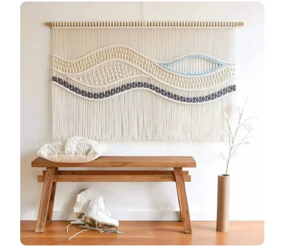 Boho weaving tapestry wall hanging with blue wave patterns above a wooden bench.