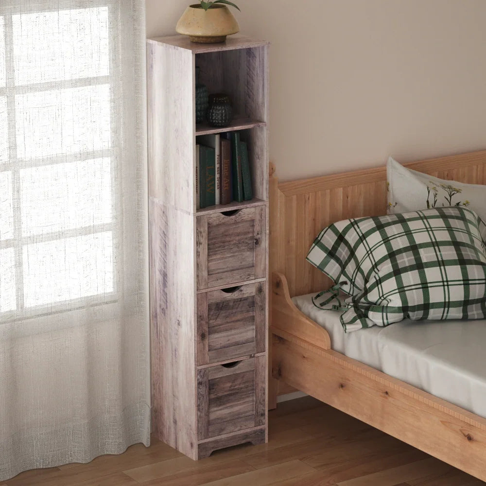 Tall narrow grey wood storage cabinet with 3 drawers and open shelves next to a bed.