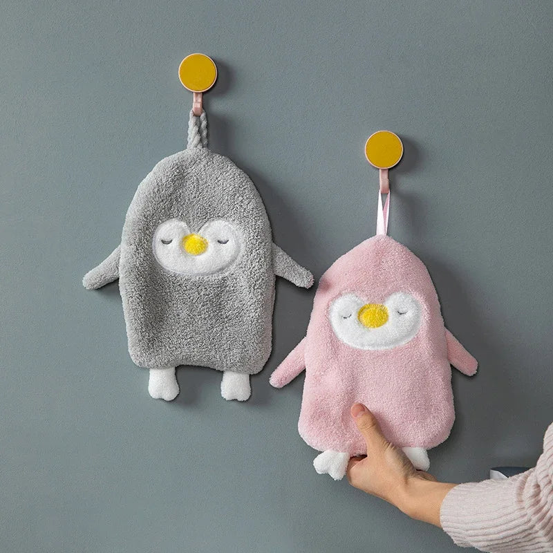 Two eprolo penguin coral velvet hand towels in grey and pink hanging on wall hooks.